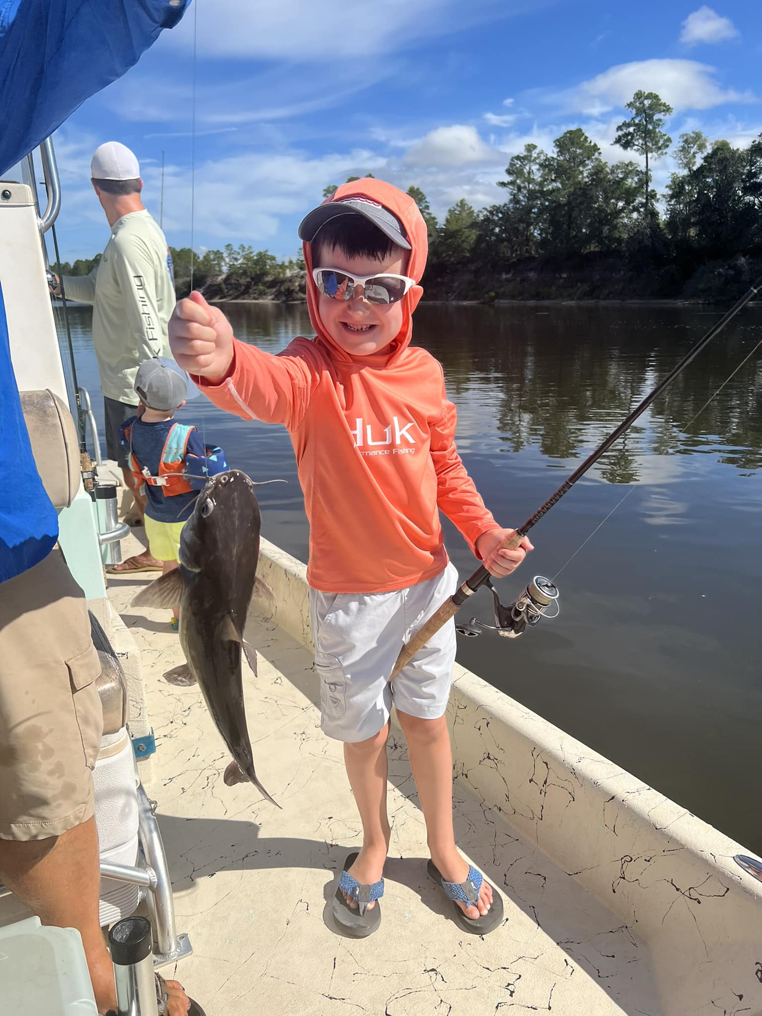 A boy holding a fish on a boat